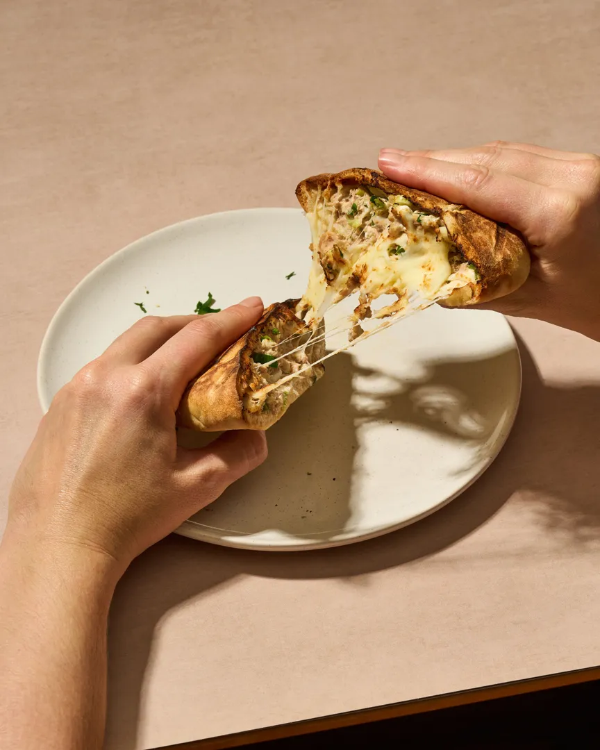 Hands pulling apart a cheesy cottage cheese stuffed flatbread